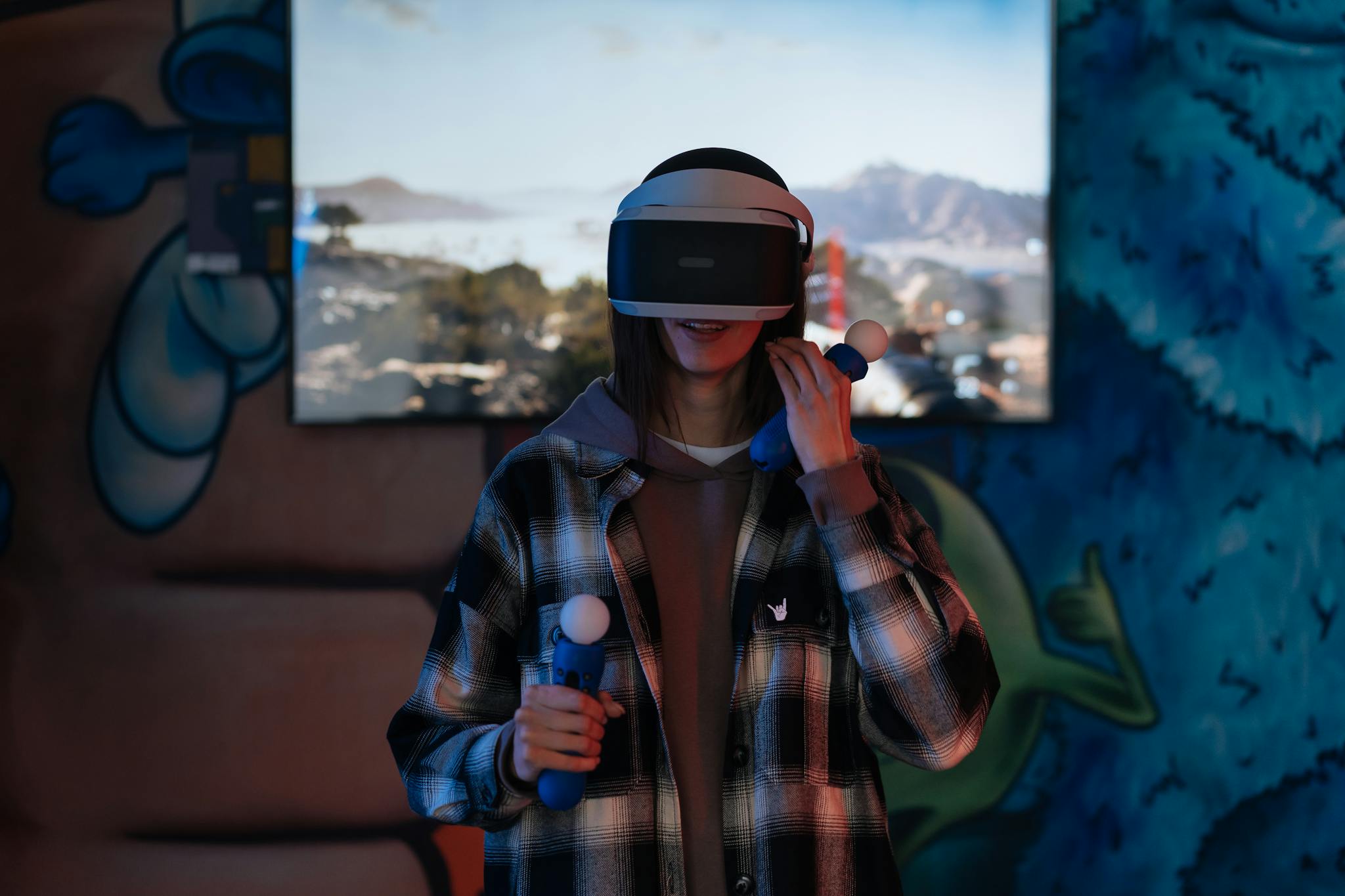 A young woman immersed in a virtual reality experience using VR goggles and controllers indoors.
